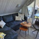 Wohnbereich mit Sofa, Stuhl und Tisch. Durchgang zu Terrasse mit Tisch und Stühlen.