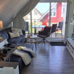 Wohnzimmer mit Sofa, TV und Balkon mit Tisch und Stühlen.