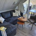 Wohnbereich mit Sofa, Stuhl und Tisch. Durchgang zur Terrasse mit Tisch und Stühlen.