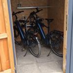 Zwei E-Bikes stehen in einem Holzschuppen mit Betonboden.