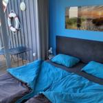 Schlafzimmer mit Bett, blauer Wand und Balkon mit Tisch und Stühlen.
