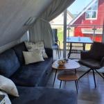 Wohnbereich mit Sofa, Stuhl und Tisch. Durchgang zur Terrasse mit Tisch und Stühlen.