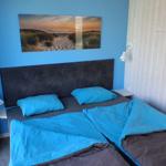 Schlafzimmer mit Bett, Wandbild und weißen Lampen.