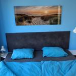 Schlafzimmer mit blauer Wand, Bett und Wandbild