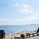 Strand mit Liegestühlen und Blick auf das Meer unter blauem Himmel.
