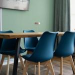 Holztisch mit vier blauen Stühlen und einer Lampe auf der Tischplatte.