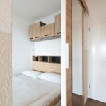 Schlafzimmer mit Bett, Holzmöbel und Schrank. Blick durch Türöffnung.