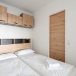 Schlafzimmer mit Bett, Holzregalen und Tür.