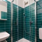Badezimmer mit Dusche, Waschbecken und Toilette. Wandfliesen in Türkis.