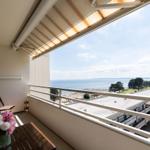 Balcony with table and chairs overlooking the sea and beach.