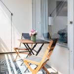 Terrasse mit Tisch, zwei Stühlen und Blumenarrangement. Durchgang zur Wohnung.