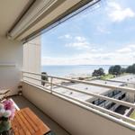 Balkon mit Tisch, Stühlen und Blumen. Blick auf Strand und Meer.