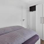 Schlafzimmer mit Bett, Kleiderschrank und Wandfernseher.