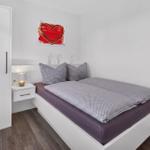 Schlafzimmer mit Bett, Nachttisch und Kleiderschrank. Wandbild mit Herz.