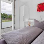 Schlafzimmer mit Doppelbett, Balkon und Wandbild mit Herz.