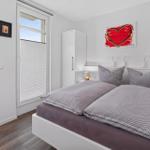 Schlafzimmer mit Doppelbett, Fenstern und Wandbild mit Herz.