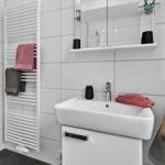 Bad mit Waschbecken, Spiegelschrank und Heizkörper mit Handtüchern.