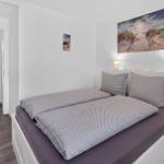 Schlafzimmer mit Bett, Wandbild und Nachttischlampen. Durchgang zu angrenzenden Räumen.