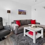 Wohnzimmer mit grauem Sofa, roten Kissen und schwarzer Relax-Sofa