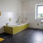 Badezimmer mit Dusche, Badewanne und gelbem Schrank.