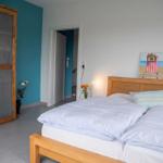 Schlafzimmer mit Doppelbett, Holzschrank und Fenster mit Blick auf Feld.