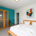 Schlafzimmer mit Bett, Kleiderschrank und Gemälde eines Hahns an der Wand.