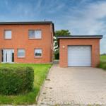 Zweistöckiges Haus mit Garagenanbau und gepflasterter Zugang
