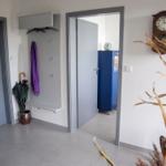Blauer Schrank mit Fenster zeigt Segelboot und Leuchtturm. Oben steht eine Glasvase.