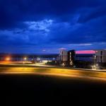 Modernes Gebäude bei Nacht mit Blick auf das Wasser und dramatischem Himmel.