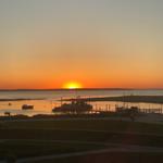 Sonnenuntergang über dem Hafen mit Booten und Steg im Vordergrund.