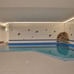 Innere Schwimmbad mit Steinwand und Fischmotiven an den Wänden.