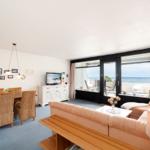 Wohn- und Essbereich mit Meerblick und Balkon. Sofa, Esstisch und TV.