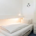 Schlafzimmer mit Bett, Nachttisch und Garderobe. An der Wand hängt ein Anker.