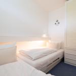Zimmer mit zwei Betten, Schrank und Anker-Dekoration an den Wänden.