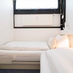 Schlafzimmer mit weißem Bett und Fenster mit Jalousie.