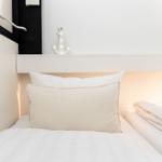 Schlafzimmer mit weißem Bett, Kissen und Anker-Dekoration an der Wand.