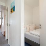 Schlafzimmer mit Bett und Kissen. Flur mit Bild an der Wand und Türöffnung.
