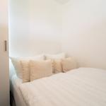Schlafzimmer mit Bett, Kissen und weißen Wänden.