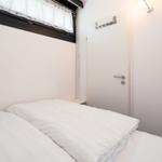Schlafzimmer mit weißem Bett, Fenster und Tür