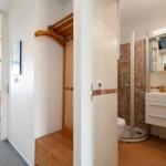 Badezimmer mit Dusche und Waschbecken. Blick in Wohnbereich mit Balkon.