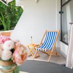Terrasse mit Liegestuhl, Tisch und Blumen im Vordergrund.