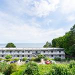 Ferienhaus mit Blick aufs Meer, umgeben von Grün und Parkplätzen.