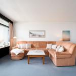 Ein Wohnzimmer mit orangefarbenem Sofa, Tisch und Fensterblick.