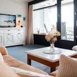 Wohnzimmer mit Sofa, Couchtisch und TV. Durchgang zur Terrasse mit Sitzgelegenheiten.