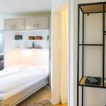 Schlafzimmer mit Bett und Küchenzeile im Hintergrund