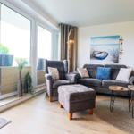 Wohnzimmer mit Sofa, Sessel und Blick auf Balkon