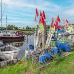 Bootshafen mit Segelyachten und roten Flaggen an Stecken