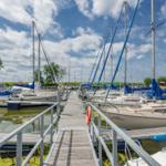 Holzsteg mit Booten im Hafen unter blauem Himmel