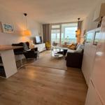 Wohnung mit Wohnbereich, Sofa, TV und großem Fenster. Holzfußboden und moderne Einrichtung.