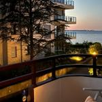 Terrasse mit Blick auf See und Gebäude bei Sonnenuntergang.